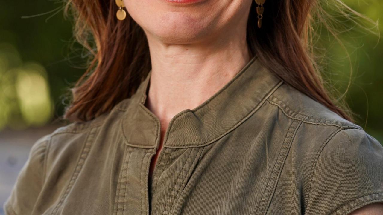 Woman with brown hair wearing a olive green dress.